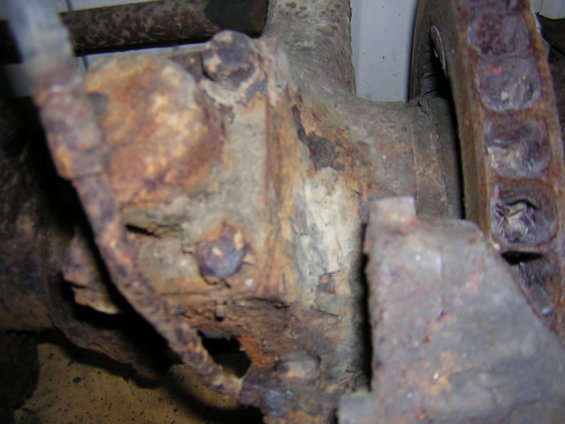 close-up of heavily rusted vehicle axle housing with bolts