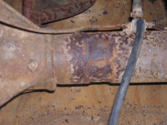 Close-up of a rusty axle housing with a black cable