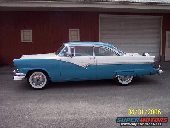 Two-tone blue and white 1955 Ford Fairlane Crown Victoria parked outside a red building