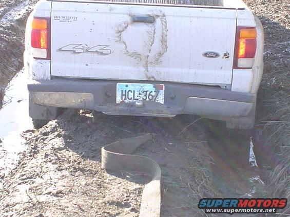Rear view of white Ford Ranger pickup truck stuck in mud, 4x4 badge visible, license plate HCL-367