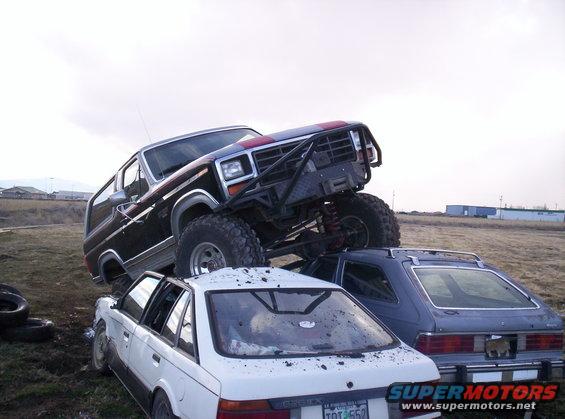 Modified dark blue SUV with red stripe on top of a white sedan and a blue hatchback