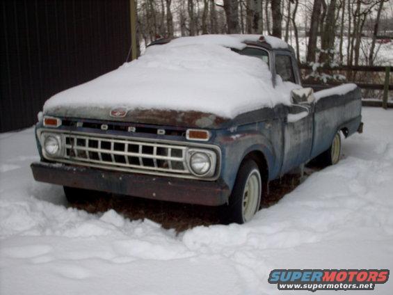 old pickup truck covered in snow, front grille visible