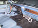1978 Dodge Monaco - The interior of a vehicle is shown, a light blue dashboard and seats, with a police radio mounted below the vents.