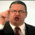 Man in suit and tie with glasses, pointing finger at viewer