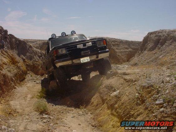 1988 Ford Bronco driving off-road in a rocky canyon, license plate 5E2F702