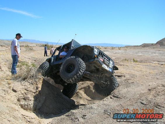 Off-road vehicle with large tires climbing out of a dirt ditch