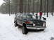 1991 Ford Bronco - A dark blue Ford Bronco is stuck in the snow with people and a dog nearby.