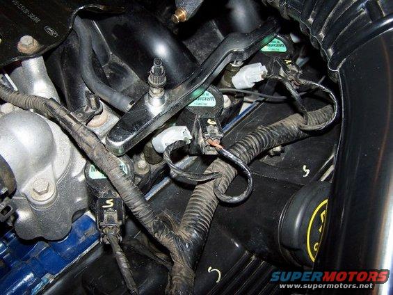 Engine wiring harness with black tape and connectors. Ford logo visible