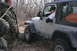 1995 Jeep Cherokee - A silver Jeep Wrangler navigates rough terrain with several people present, suggesting an off-road excursion.