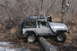 1995 Jeep Cherokee - A person is looking at a silver Jeep Wrangler TJ that is stuck on a log in a wooded area.