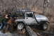 1995 Jeep Cherokee - A group of people push a silver Jeep Wrangler Rubicon stuck in a wooded area.