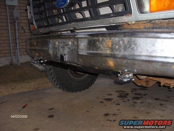 Front bumper and grille of a weathered 1980s Ford Bronco with a custom hitch installed