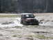 2004 Dodge 2500 - A red Jeep Wrangler navigates a muddy terrain, with "Off Road" visible on the windshield.