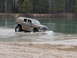 2004 Dodge 2500 - Muddy SUV navigates through a body of water, kicking up spray.