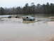 2004 Dodge 2500 - An SUV is partially submerged in water, with two ATVs navigating the shallow area.