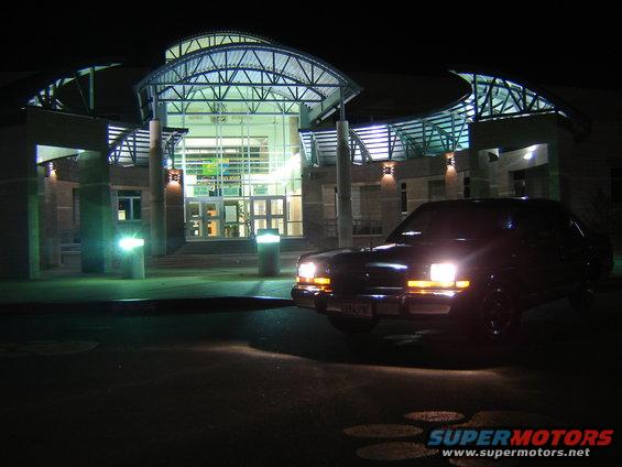 Dark 1988 Ford Crown Victoria LTD parked at night in front of a modern building