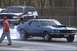 1969 Ford Mustang - A blue 1969 Ford Mustang performs a burnout on the drag strip, with an SUV in the background.