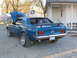 1969 Ford Mustang - Rear view of a blue 1969 Ford Mustang, showing its spoiler and custom wheels, with the hood popped open.