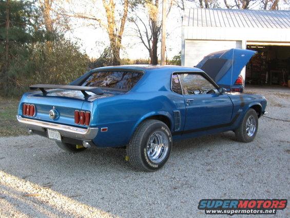 Blue 1969 Ford Mustang fastback parked outside a garage with hood open