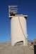 1979 Ford Bronco - A tall, cylindrical industrial structure stands on a dusty, barren landscape under a bright blue sky.