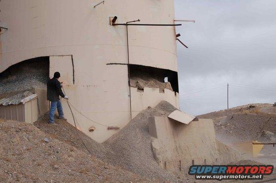 Demolition of an industrial silo with a worker using a torch