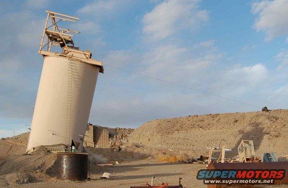 Tilted industrial silo in a desert landscape with debris
