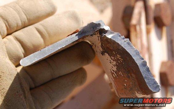 Broken metal part held in gloved hand, showing rust and chipped paint