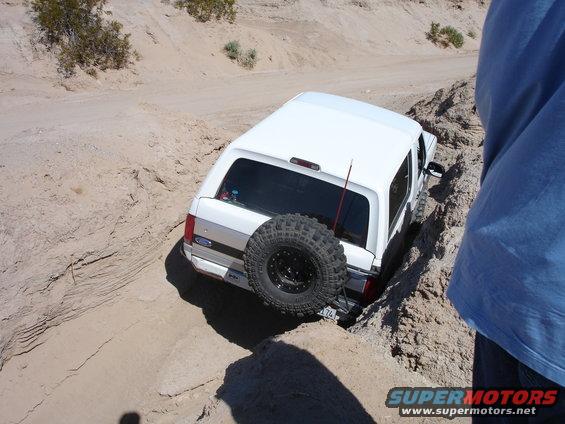 1996 Ford Bronco with spare tire mounted on rear, stuck in a sandy off-road rut