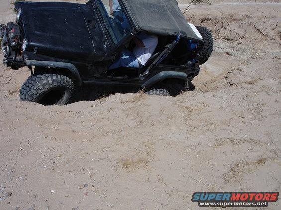 Black Jeep Wrangler stuck in sand, side view