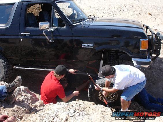 Black 1996 Ford Bronco with people working on the front passenger wheel