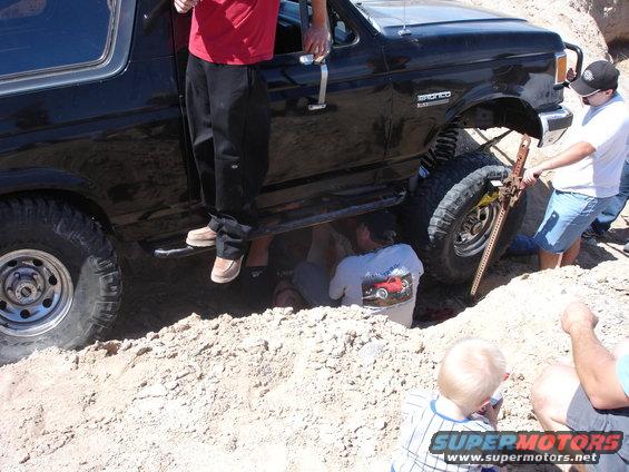 1996 Ford Bronco stuck in dirt with people using a jack to lift it