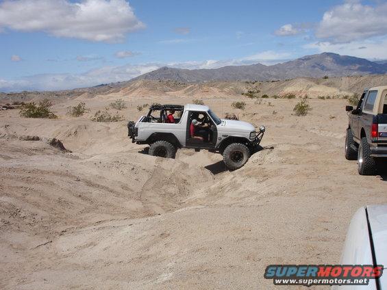 White Bronco navigating sandy terrain with another Bronco nearby