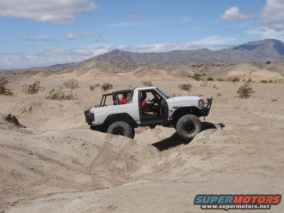 White off-road SUV with doors removed, navigating sandy terrain
