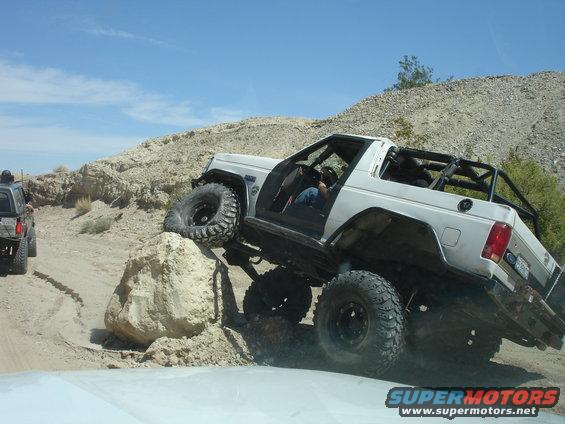 1996 Ford Bronco climbing a rock on a dirt trail, another SUV behind it