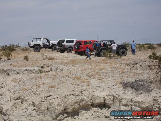1996 Ford Bronco and three other off-road vehicles parked on a desert landscape