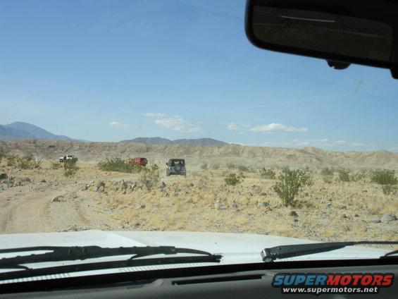 Three SUVs on a desert road, viewed from inside a vehicle