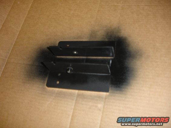 Two black metal brackets on a cardboard surface