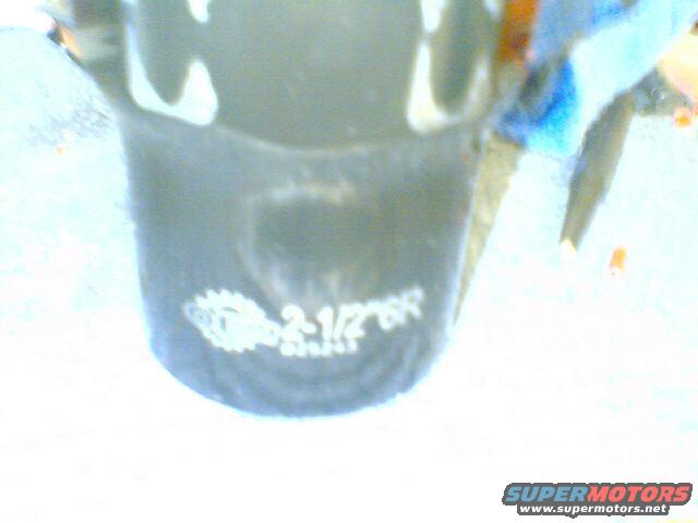 Black automotive part with white text reading "2-1/2" and a gear logo