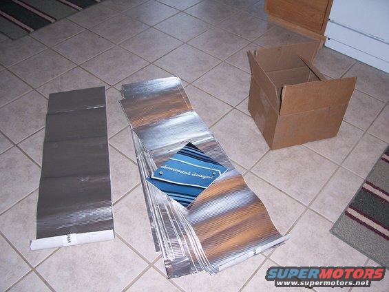 Sound deadening material sheets and a cardboard box on a tiled floor