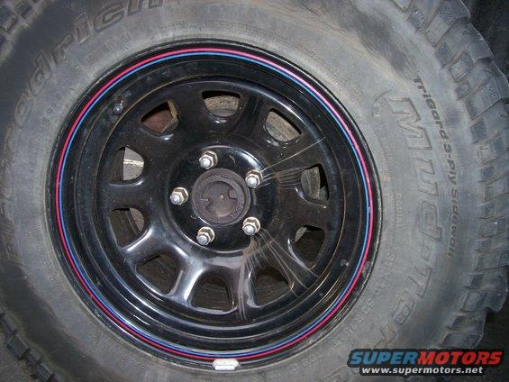 Black steel wheel with red and blue trim rings on a BFGoodrich tire