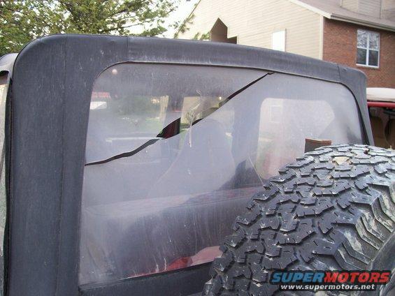 Jeep Wrangler TJ soft top rear window with a large crack; spare tire visible