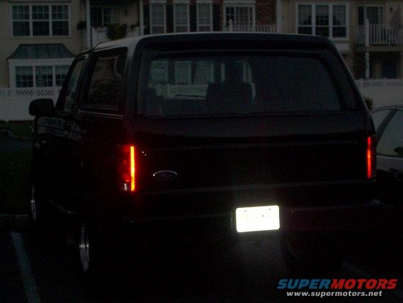 Dark SUV's rear end, showing vertical taillights and a license plate