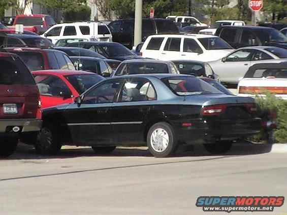 1994 Ford Probe sedan, side view, parked in a lot with other vehicles