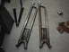 1978 Ford Bronco - These are two metal radius arms, likely for a vehicle's suspension system, lying on a garage floor.