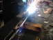 1978 Ford Bronco - A close-up view of a metal part being welded, with sparks flying in a workshop environment.