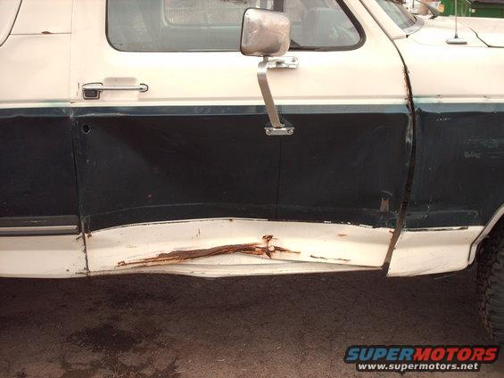 1988 Ford Bronco side door with significant rust and damage along the lower body panel