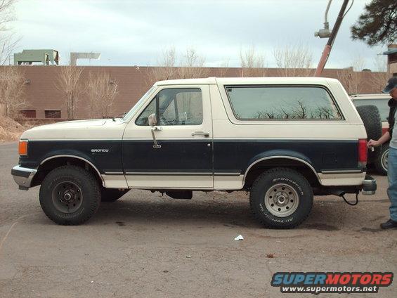 Two-tone blue and white Ford Bronco, side view. Visible "Bronco" badge on fender