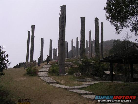 Stone pillars and a pavilion on a misty hillside with a paved path