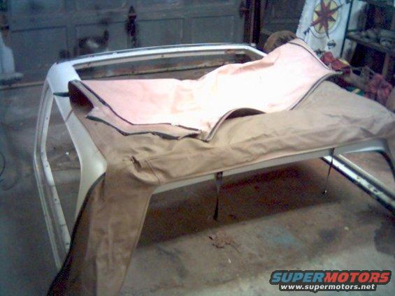 soft top frame with tan and pink fabric draped over it, inside a garage