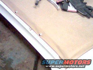 Gloves, hammer, and pliers on a tan soft top material with a white trim piece